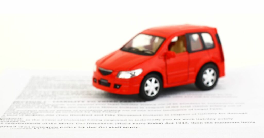 Voiture miniature rouge sur contrat d'assurance